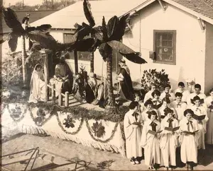 Nativity scene float with costumed choir in front of a building.