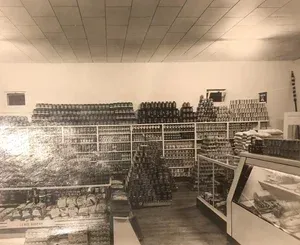 Interior of a vintage grocery store with shelves stocked with canned goods and refrigerators.