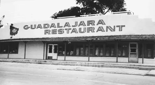 Guadalajara Restaurant in black and white. Exterior shot of a building with large sign above the entrance.