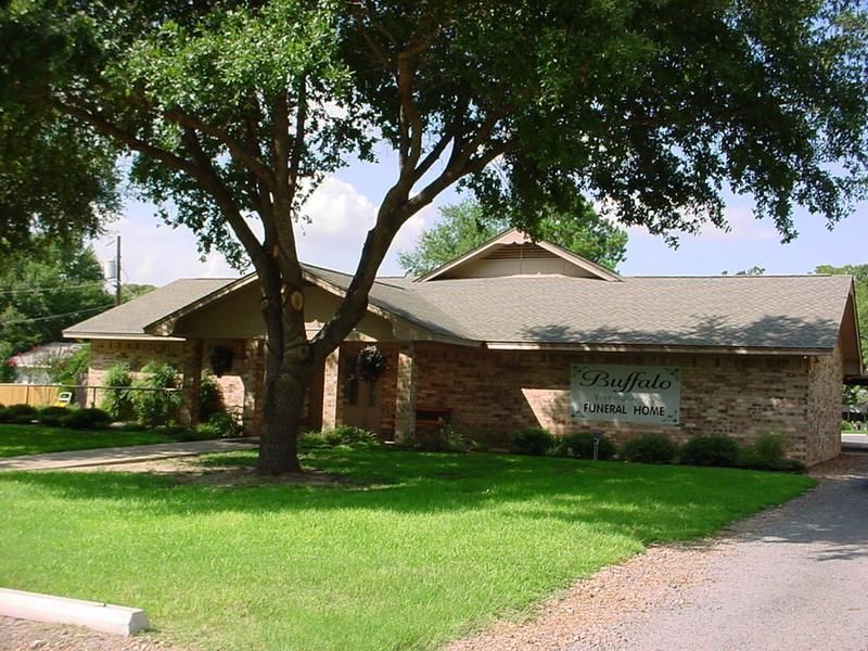 a brick house with a tree in front of it and a sign that says emeralds