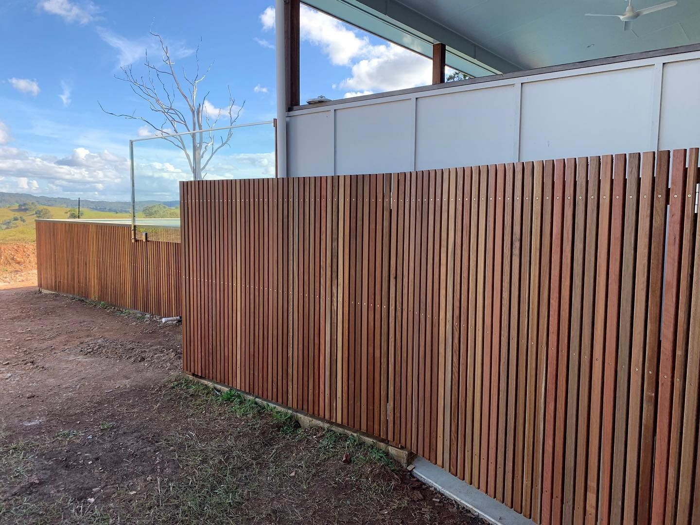 Wooden slatted fence alongside a building with a blue sky background. — HinterCoast Pools In Wolvi, QLD