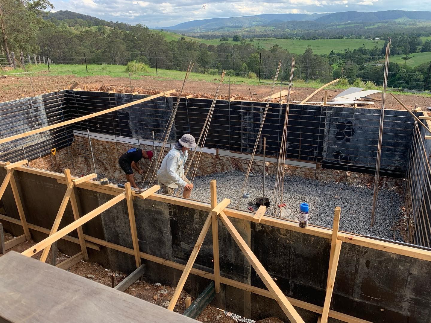 Workers constructing concrete pool frame outdoors, surrounded by scenic landscape. — HinterCoast Pools In Wolvi, QLD