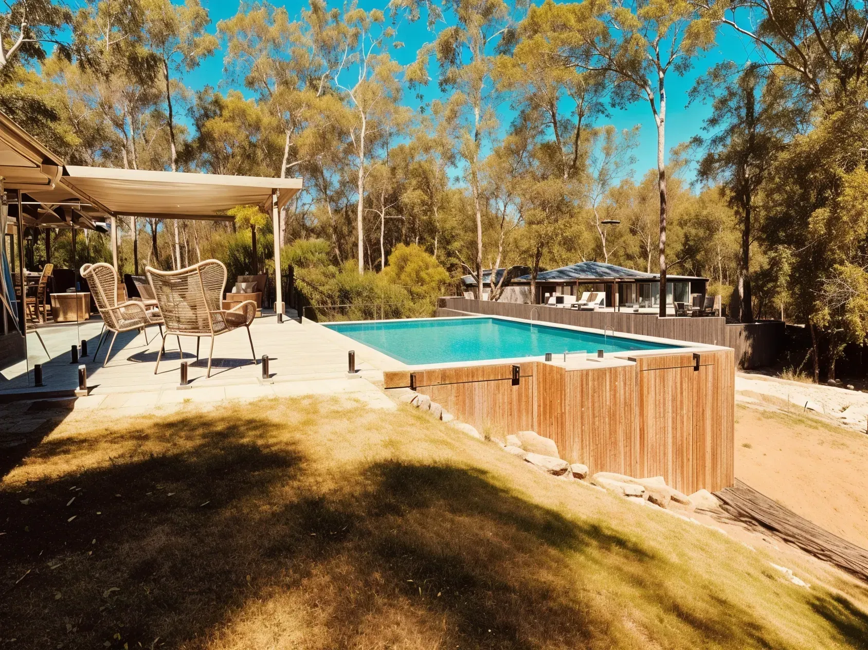 Outdoor pool bordered by wooden fence, patio with seating, surrounded by trees under a bright blue sky — HinterCoast Pools In Mary Valley, QLD