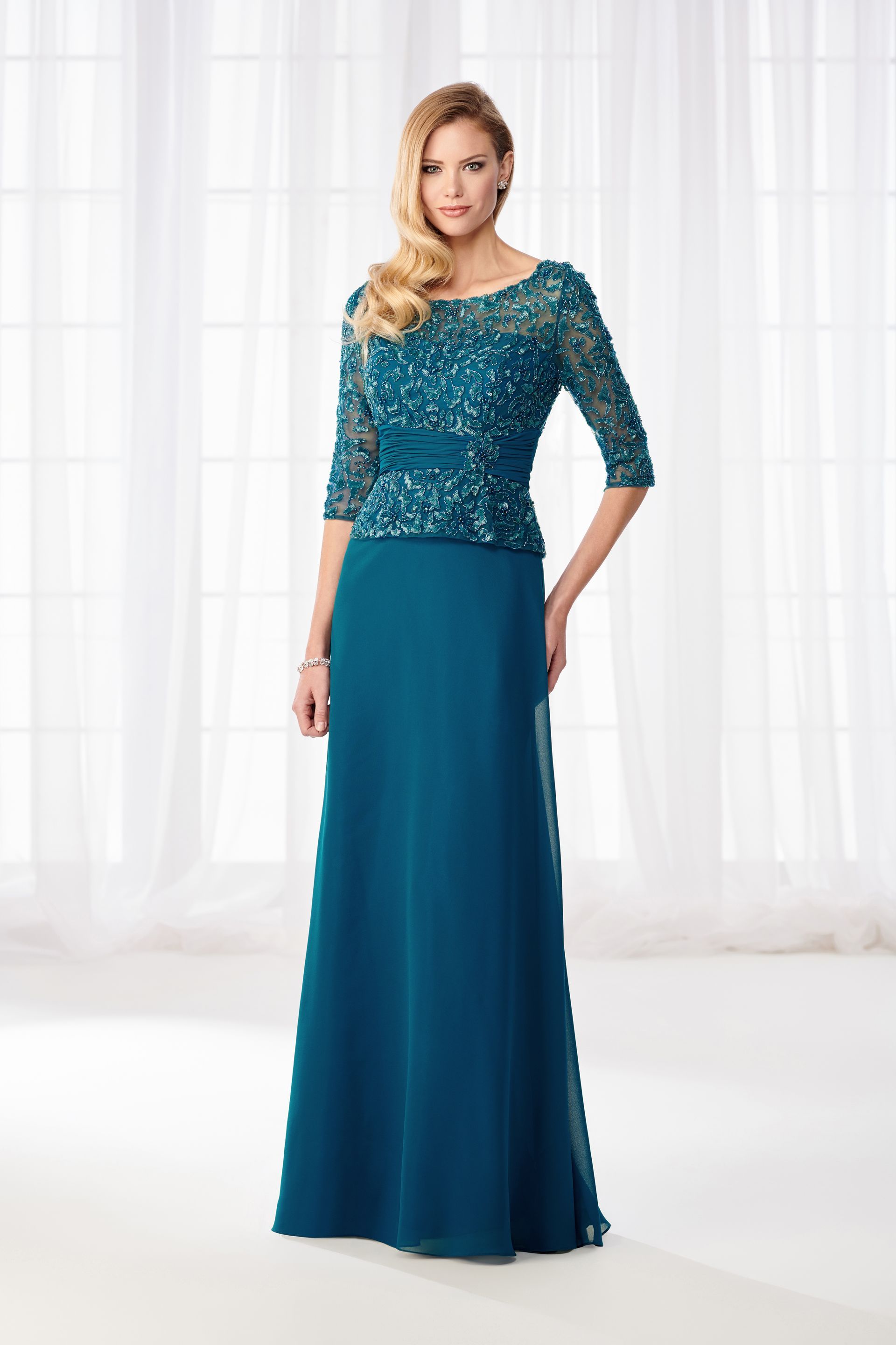 A woman is wearing a teal mother of the bride dress.