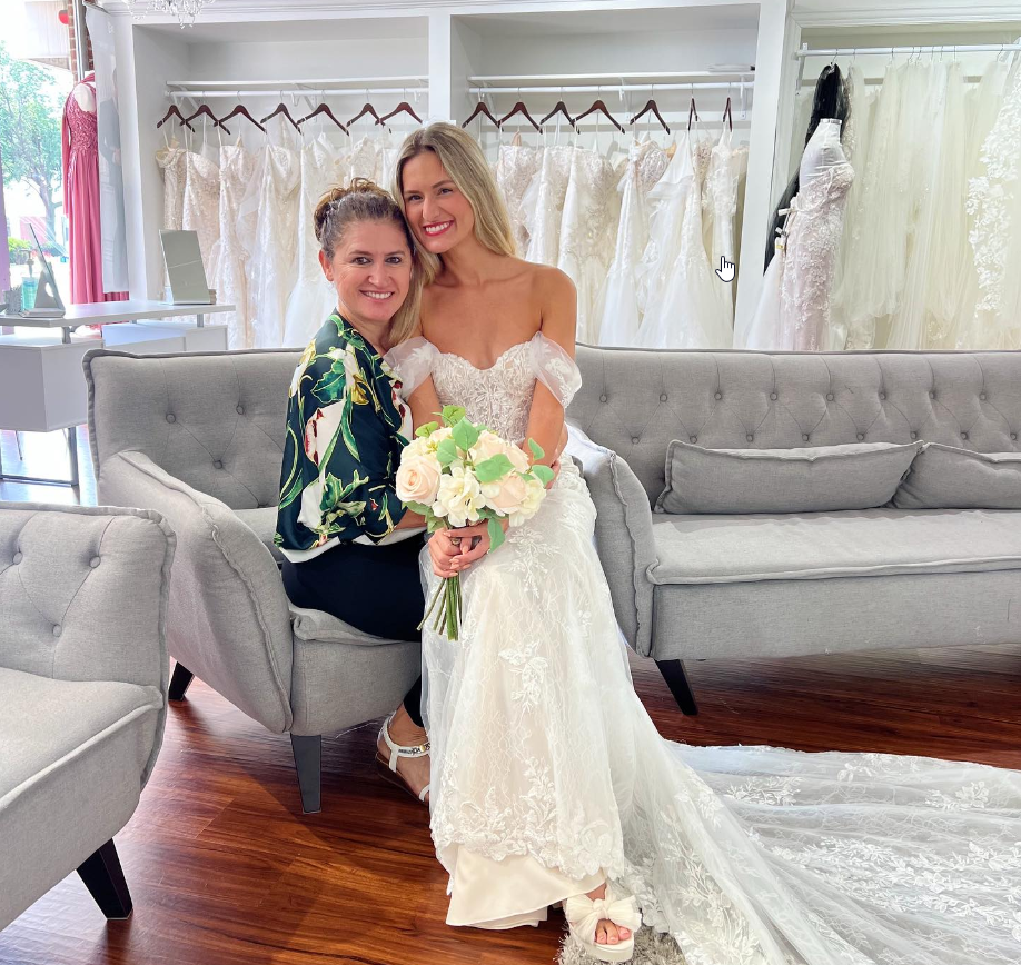 A woman in a wedding dress is posing for a picture with another woman