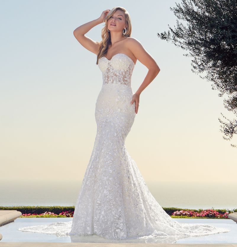 Woman in wedding dress stands before a decorative arched doorway, floral arrangements.