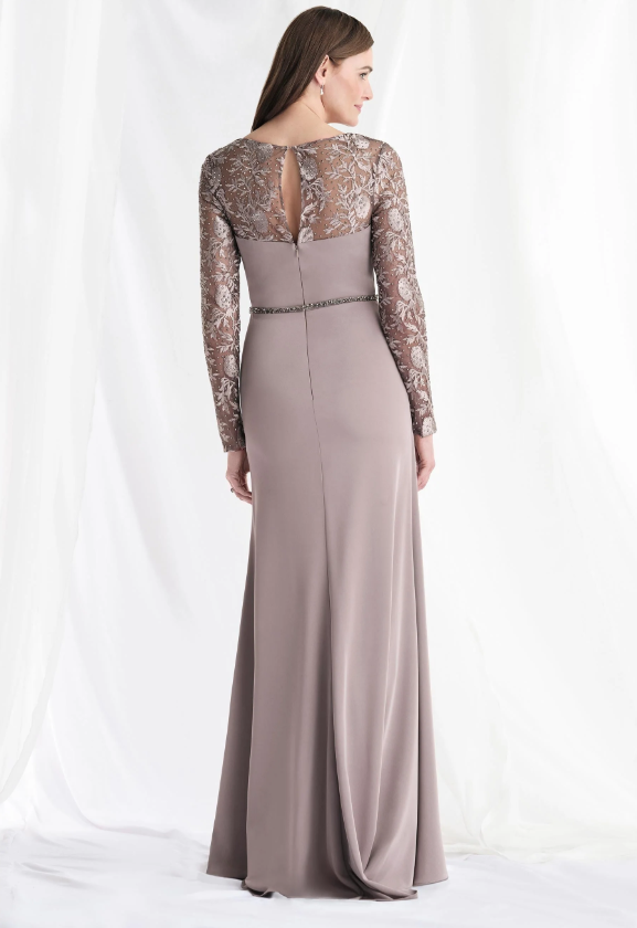 Woman in a long, mauve dress with lace sleeves and back, standing against a white backdrop.