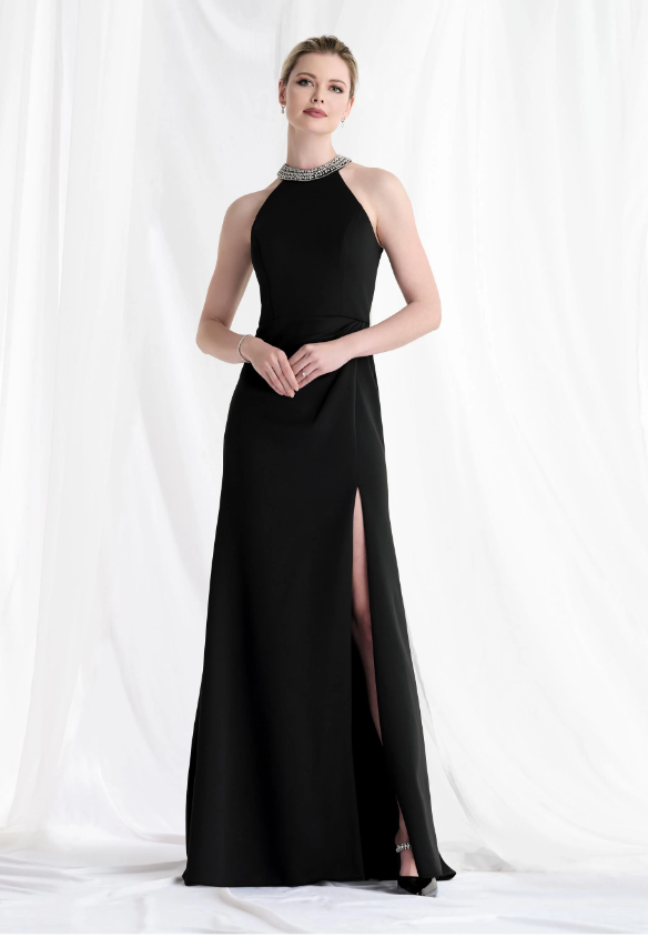 Woman in a black halter-neck evening gown with a high slit, standing in front of white curtains.