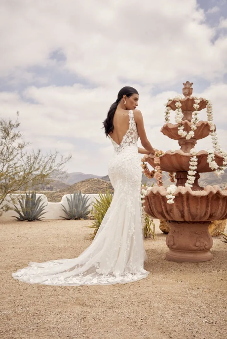A woman in  Beloved wedding dress BL430 is standing next to a fountain.