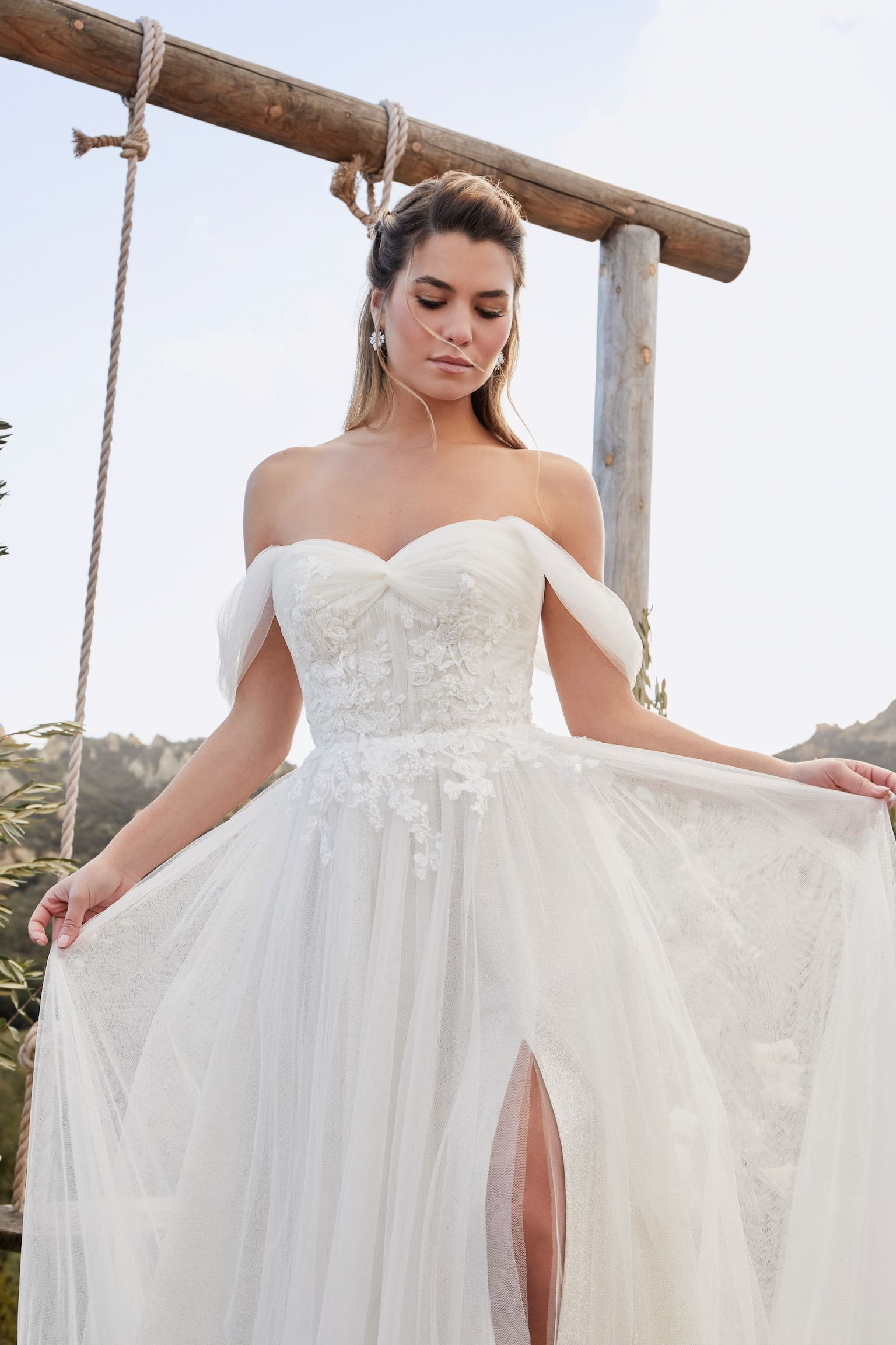 A woman in a white wedding dress is standing next to a swing.