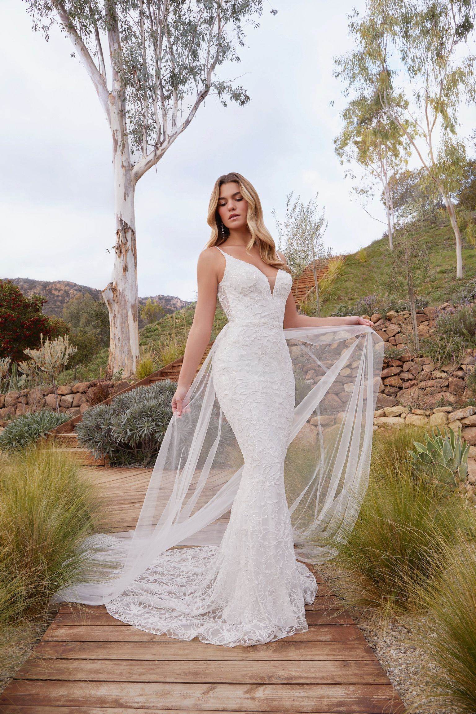 A woman in a wedding dress is standing on a wooden bridge.