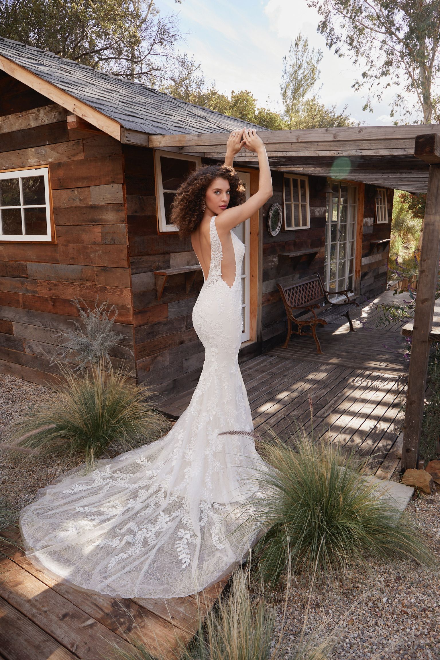 A woman in a wedding dress is standing in front of a wooden cabin.