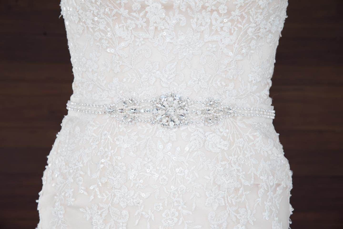 A close up of a wedding dress on a mannequin on a wooden table.