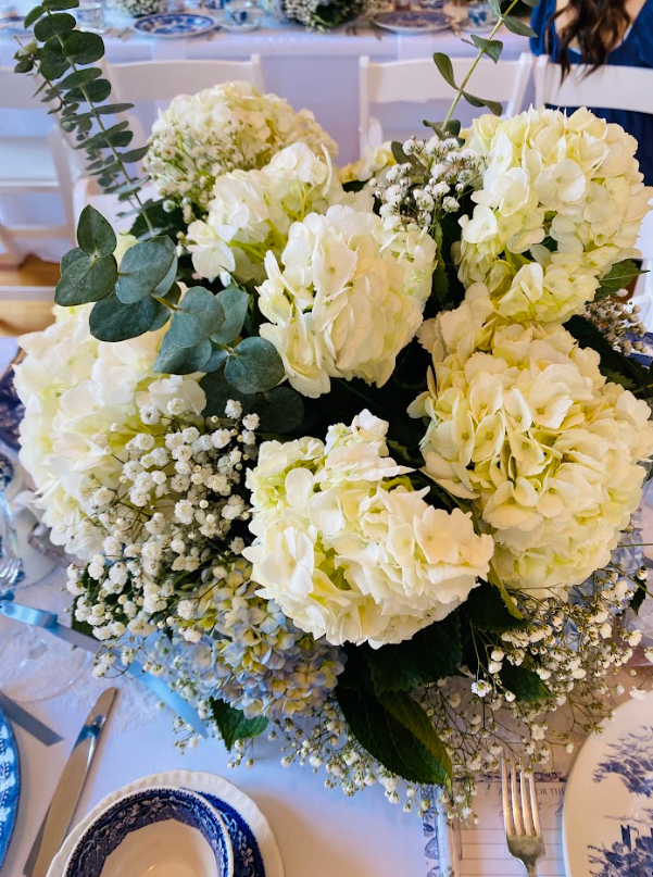 A vase filled with white flowers and baby 's breath is on a table.