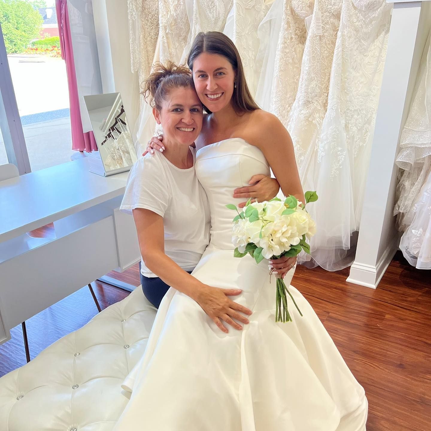 A woman in a wedding dress is posing for a picture with another woman.
