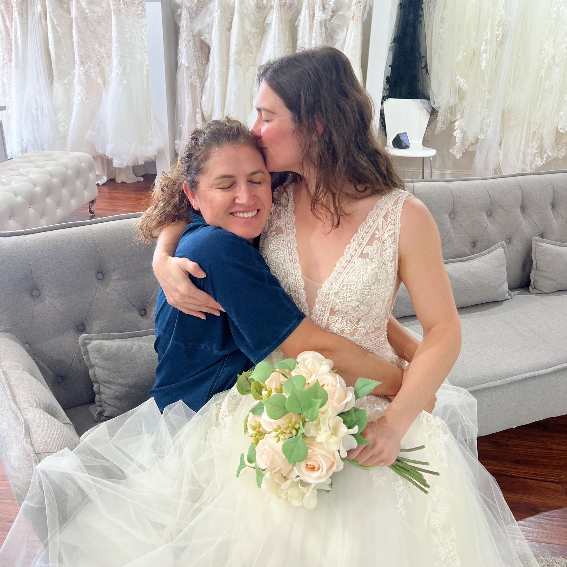 A woman in a wedding dress kisses another woman on the cheek