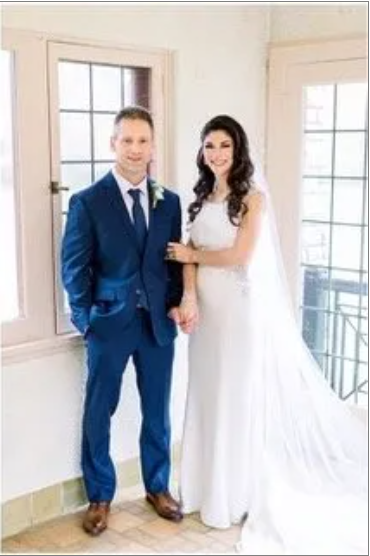 A bride and groom are posing for a picture in front of a window.