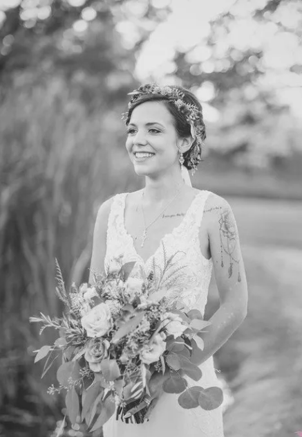 A black and white photo of a bride holding a bouquet of flowers.