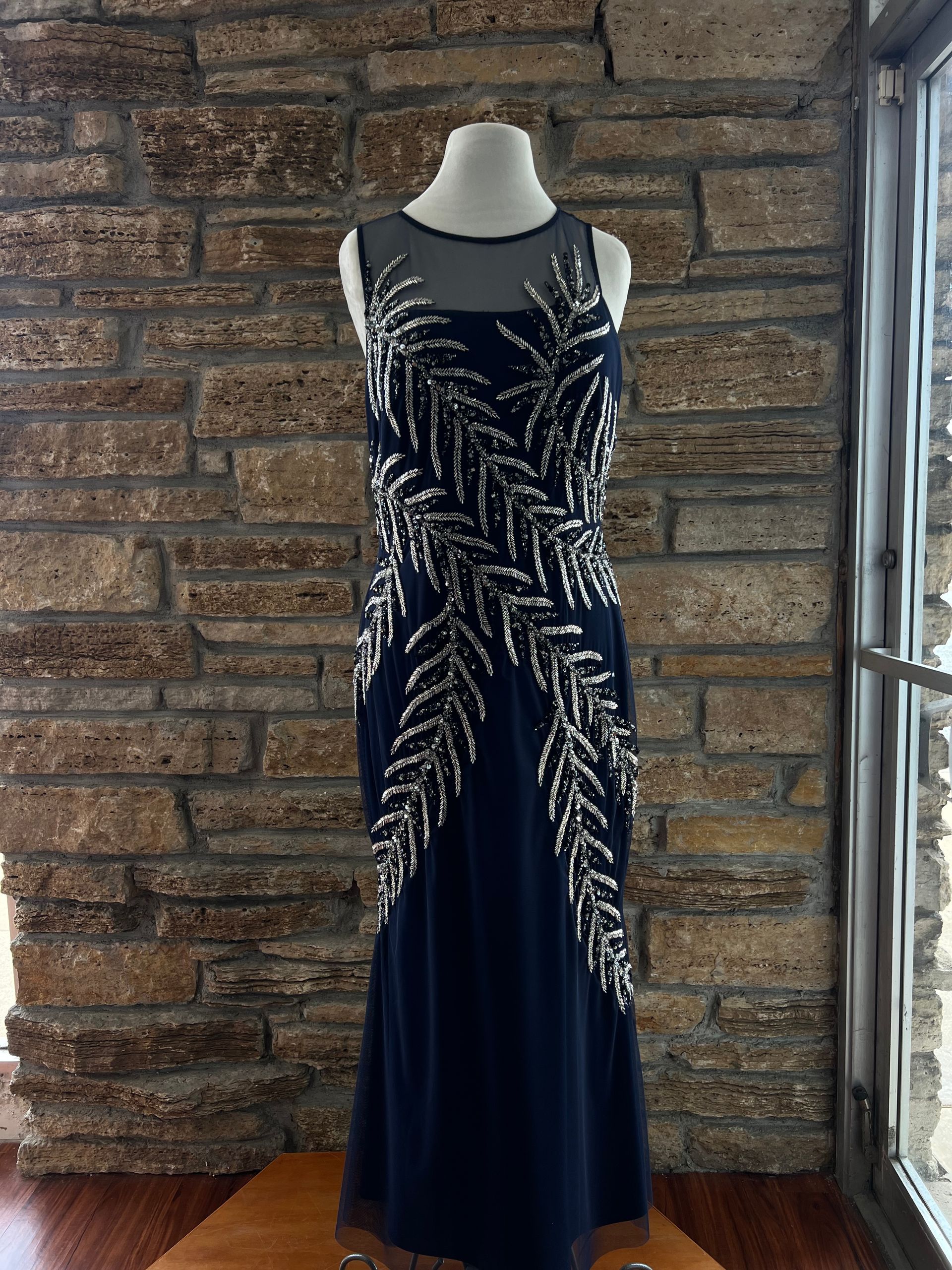 Navy blue formal gown with silver sequin leaf design on a mannequin.