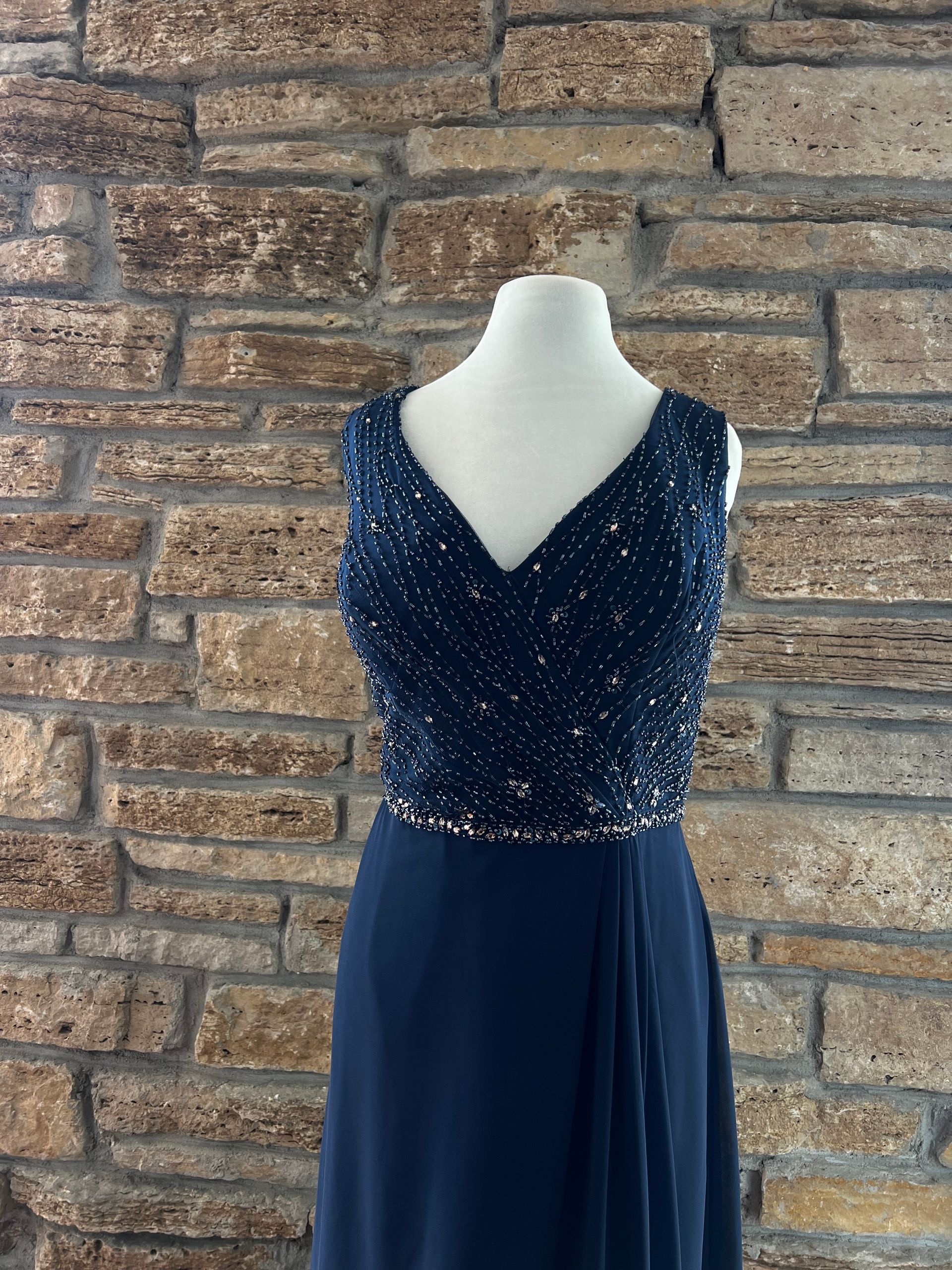 Navy blue beaded bodice formal dress on a mannequin, against a brick wall.