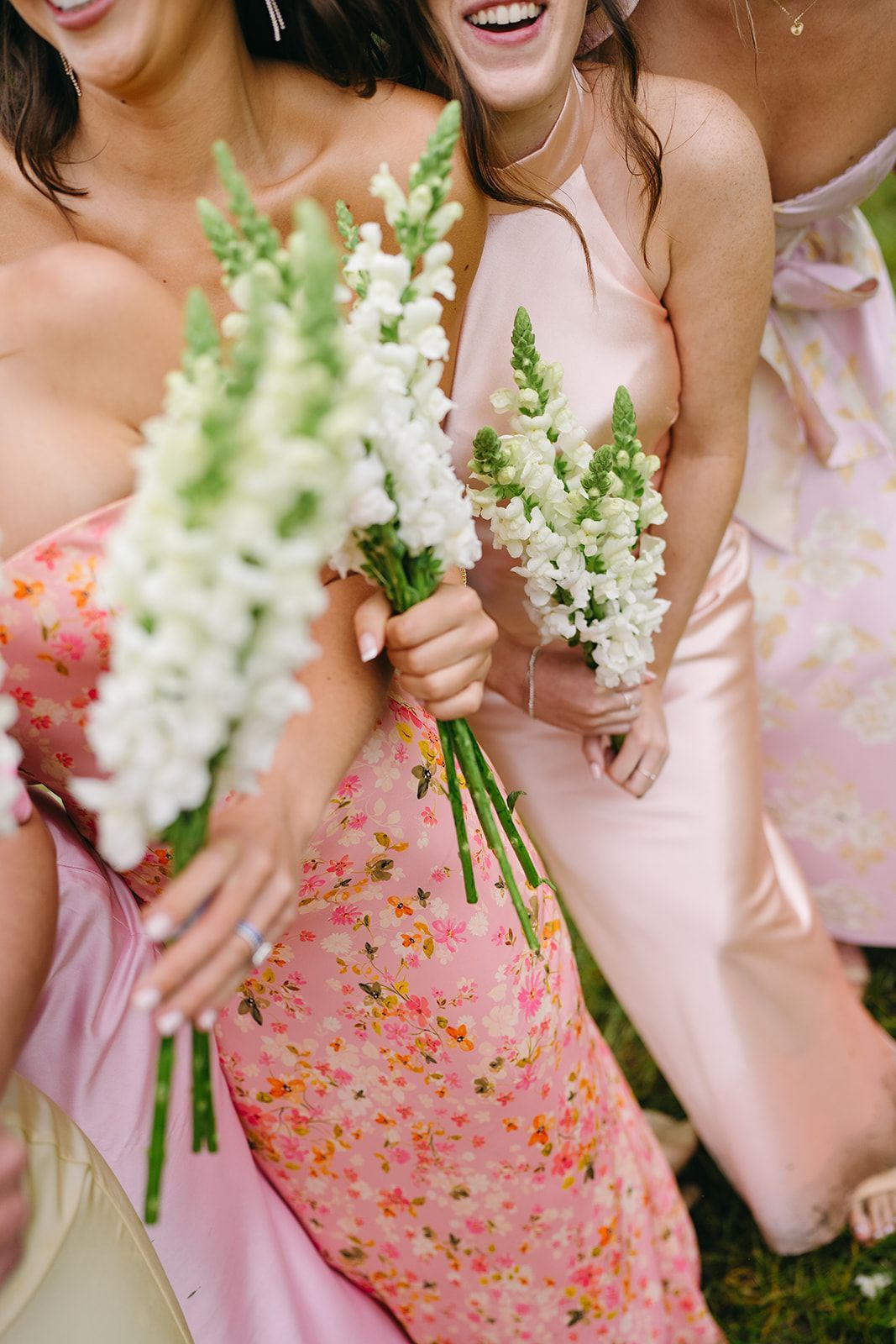 A group of bridesmaids in pink dresses are holding bouquets of white flowers.