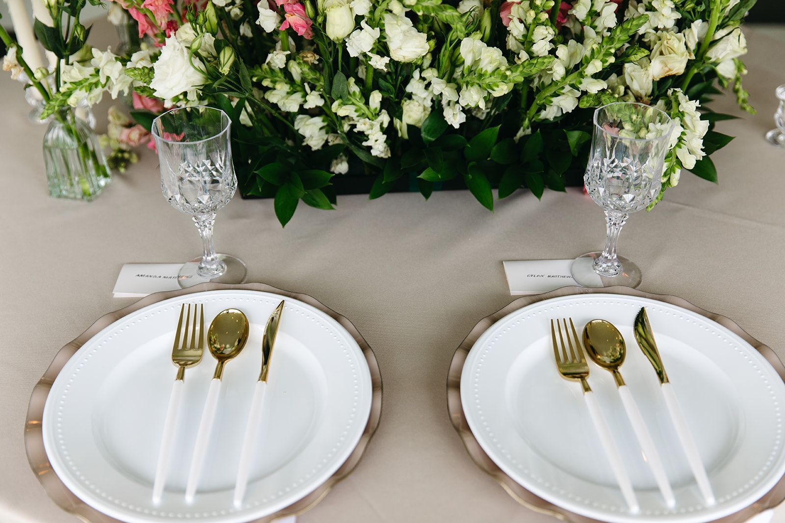 Two plates with silverware and a vase of flowers on a table.