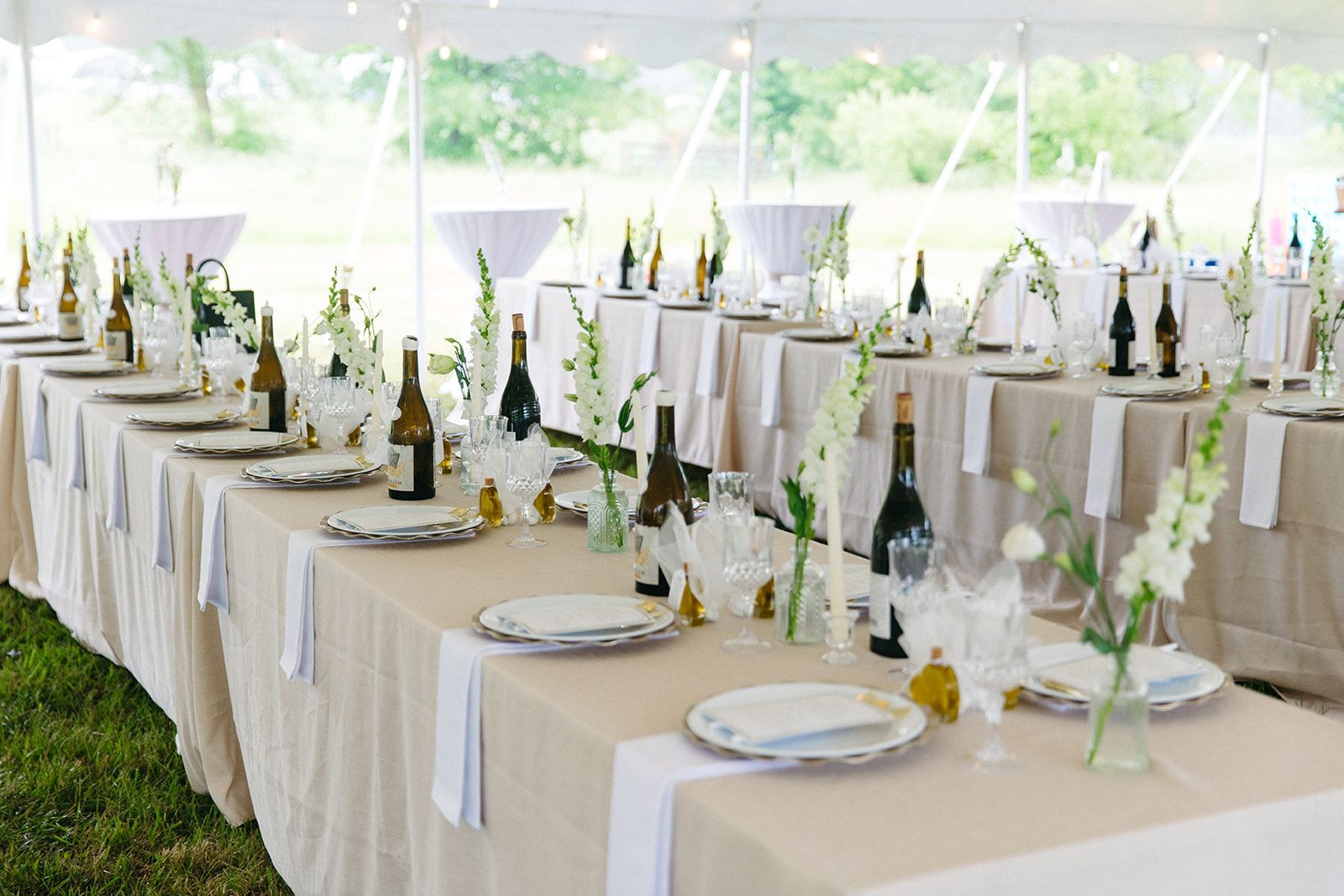 A long table is set for a wedding reception under a tent.