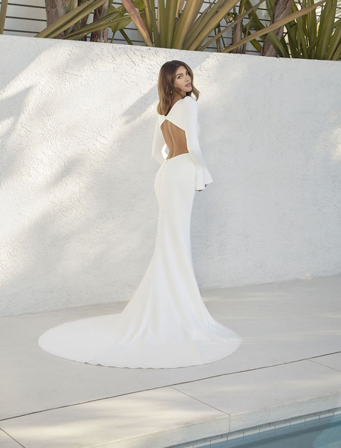 A woman in a white dress is standing next to a pool.