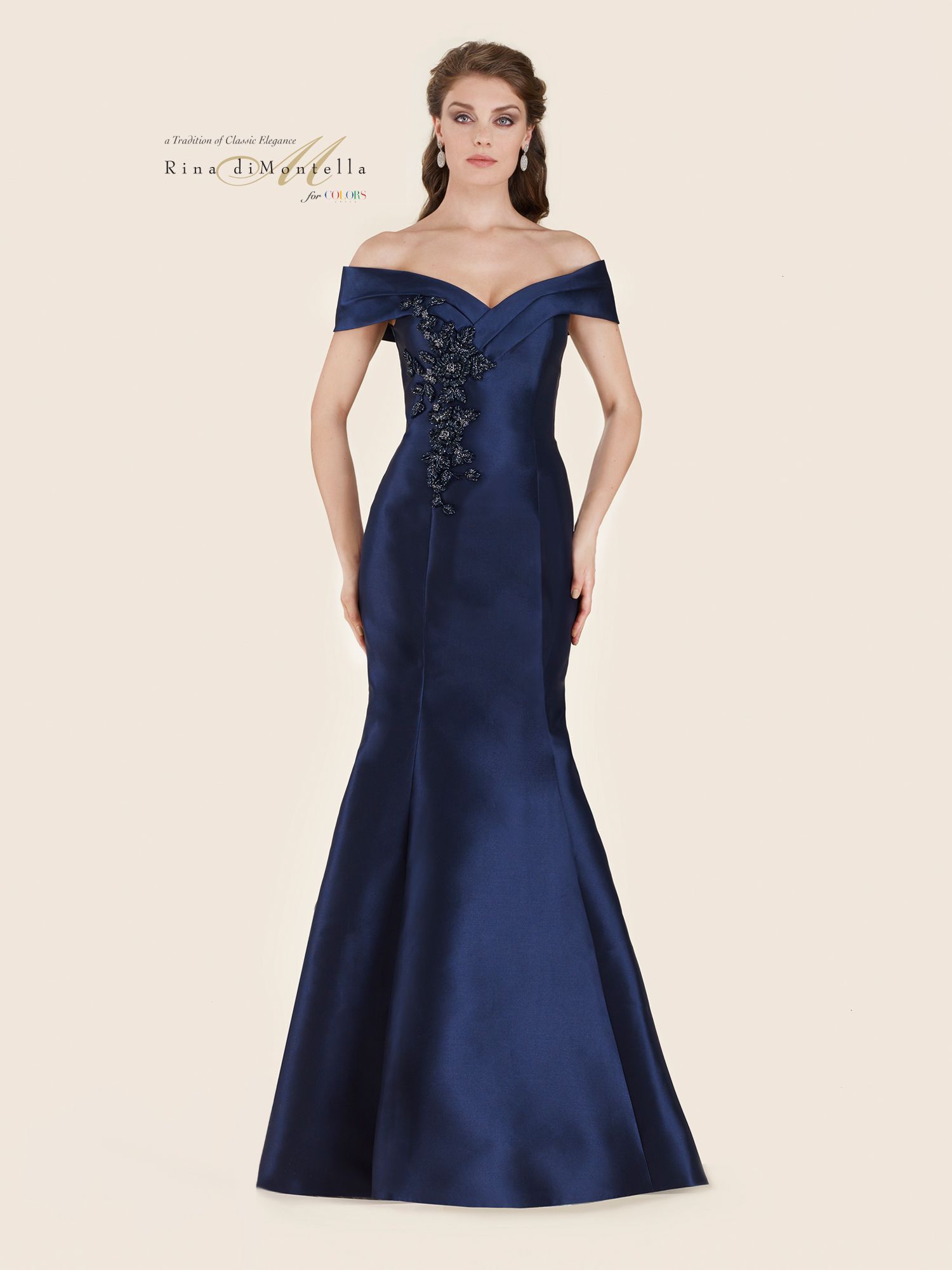 A woman is wearing a long blue off the shoulder dress.