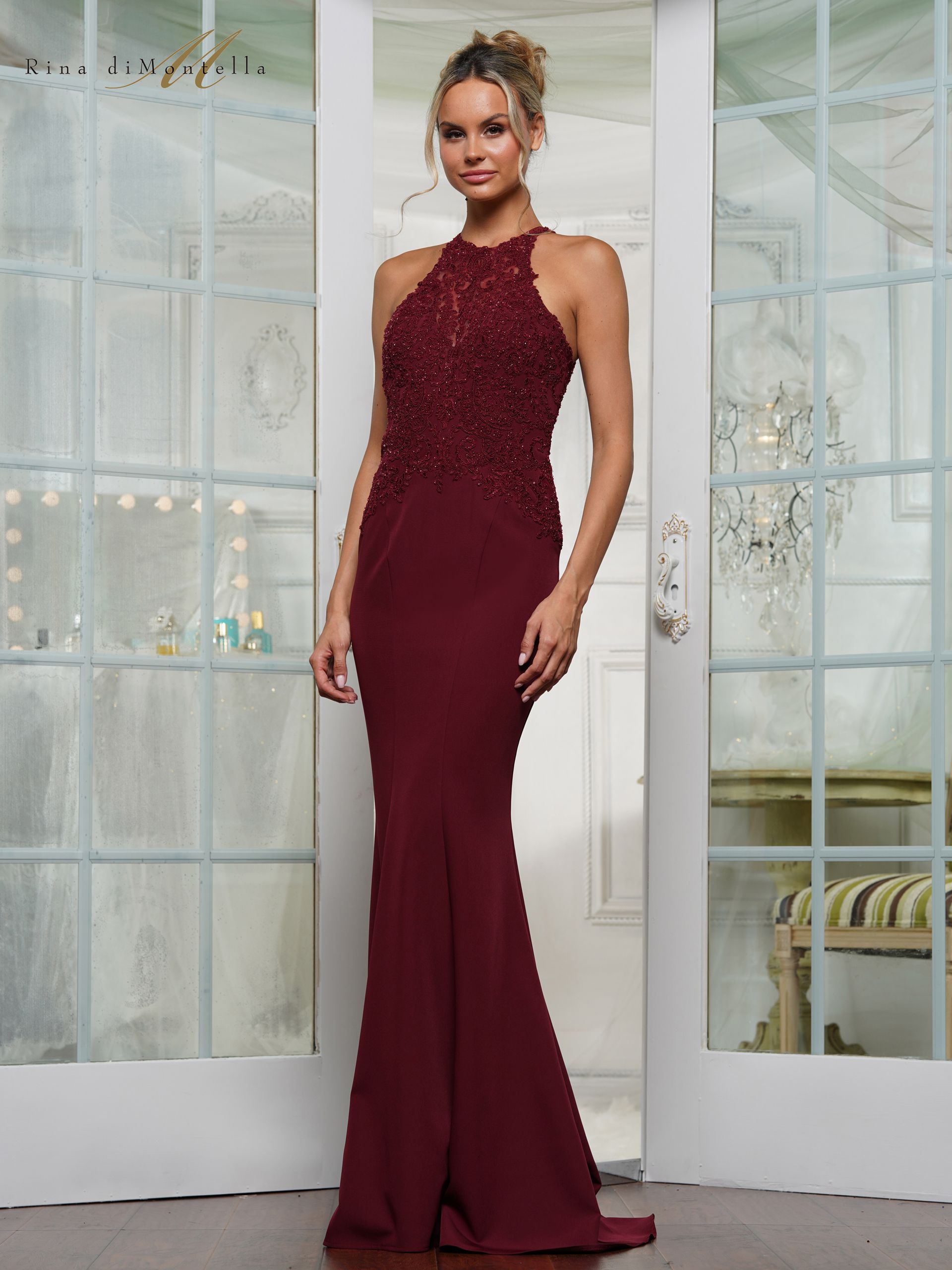 A woman in a burgundy dress is standing in front of a door.