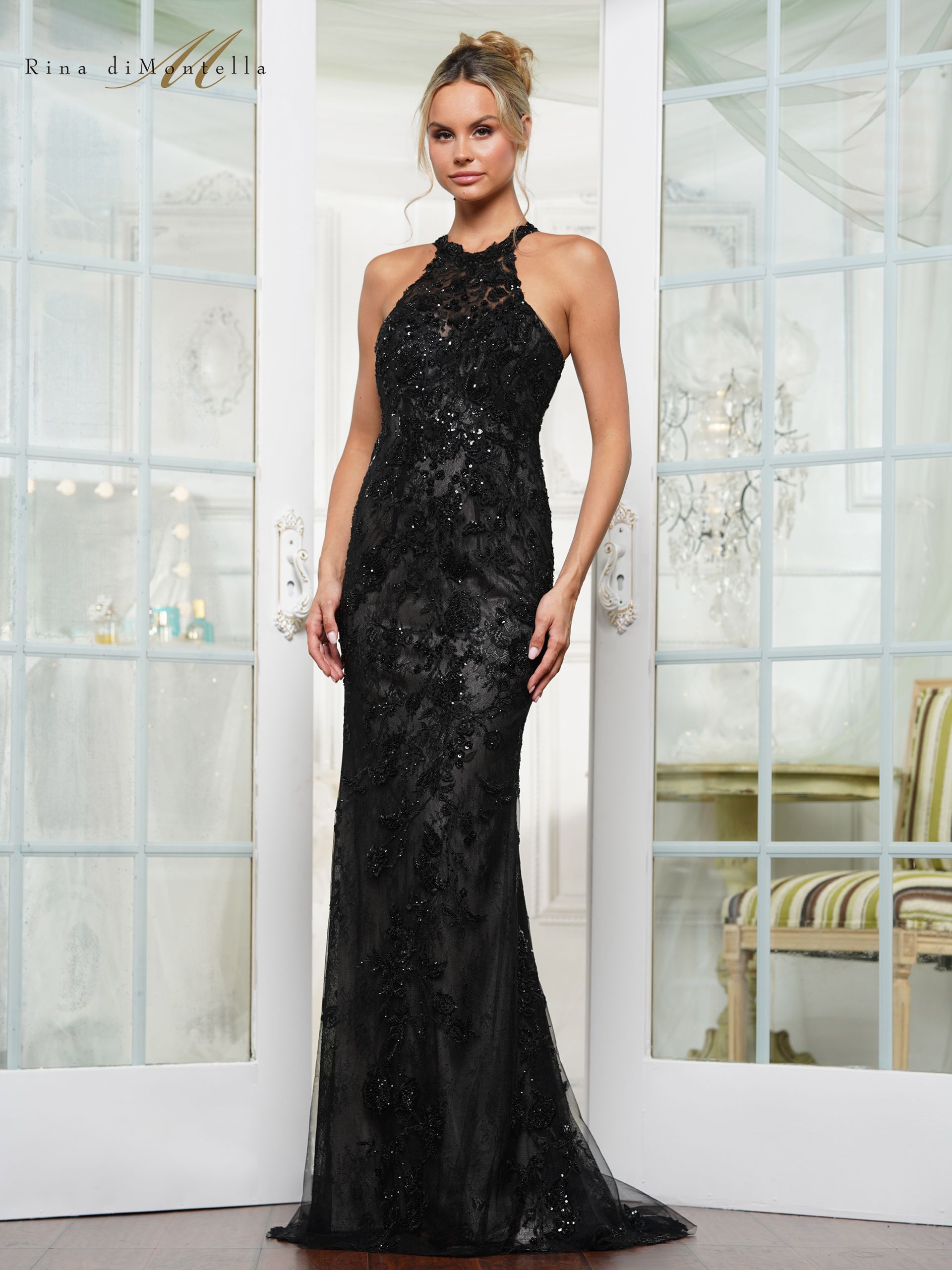 A woman in a black dress is standing in front of a glass door.