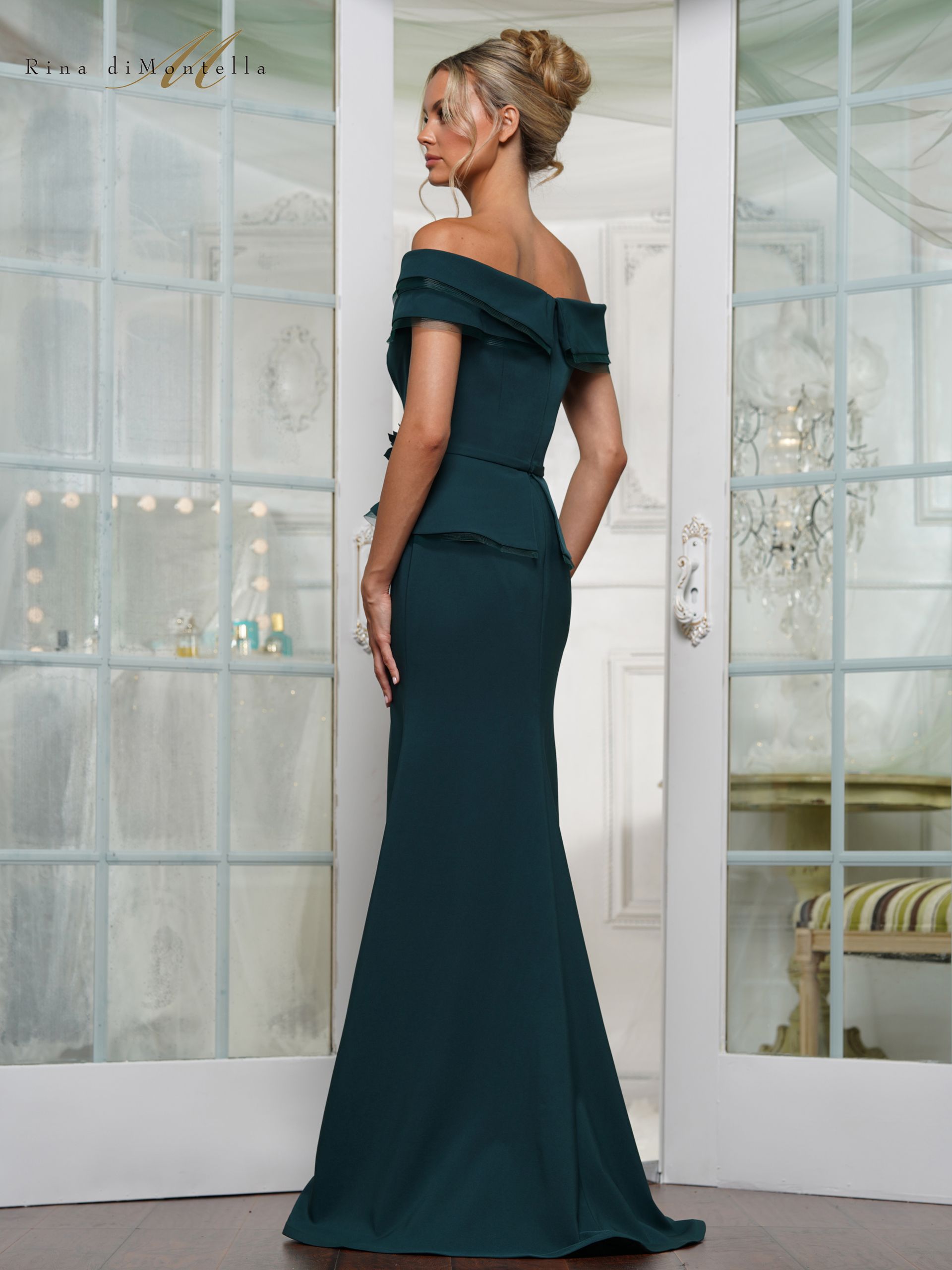 A woman in a long green dress is standing in front of a door