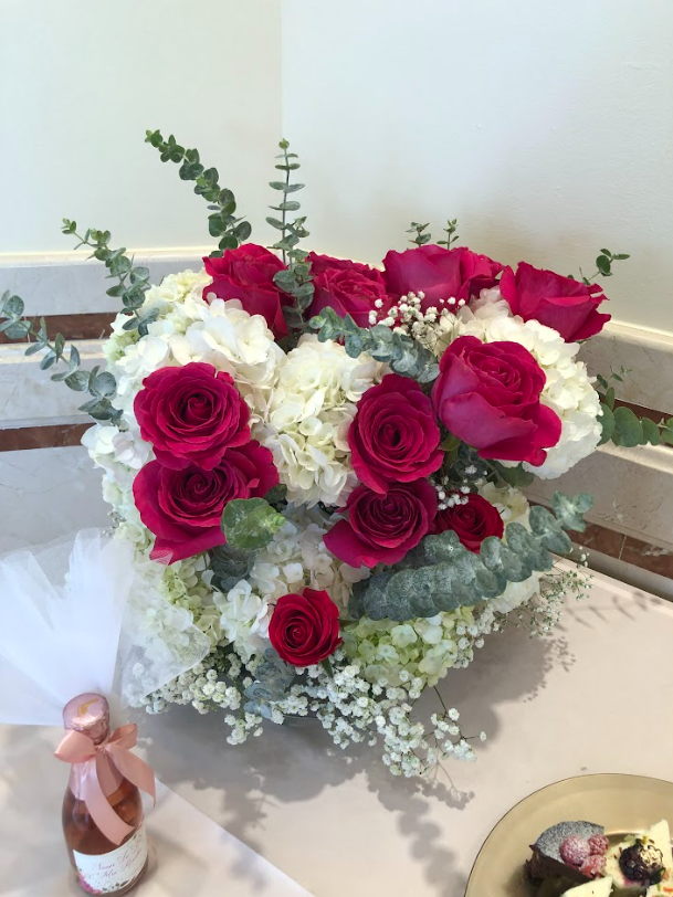 A heart shaped vase filled with pink and white flowers