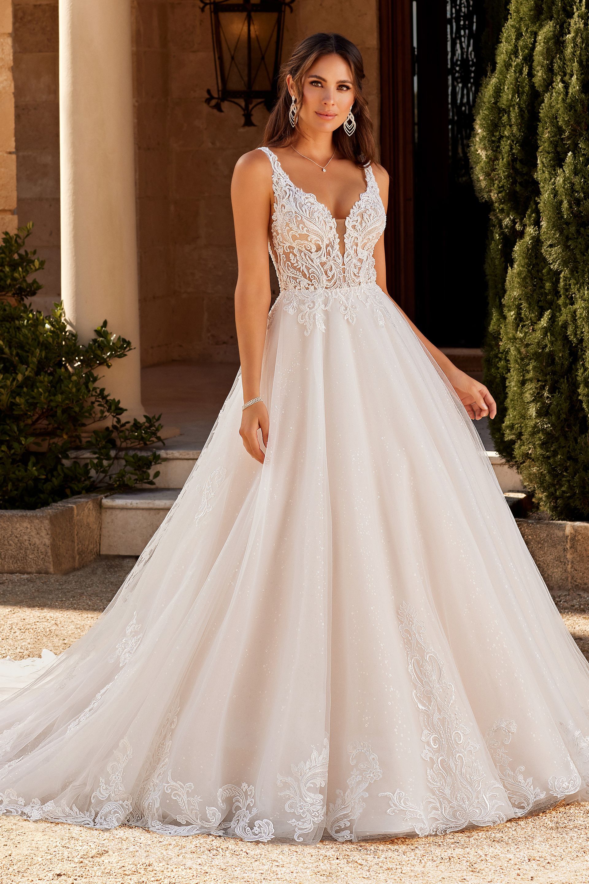 A woman in a white wedding dress is standing in front of a building.