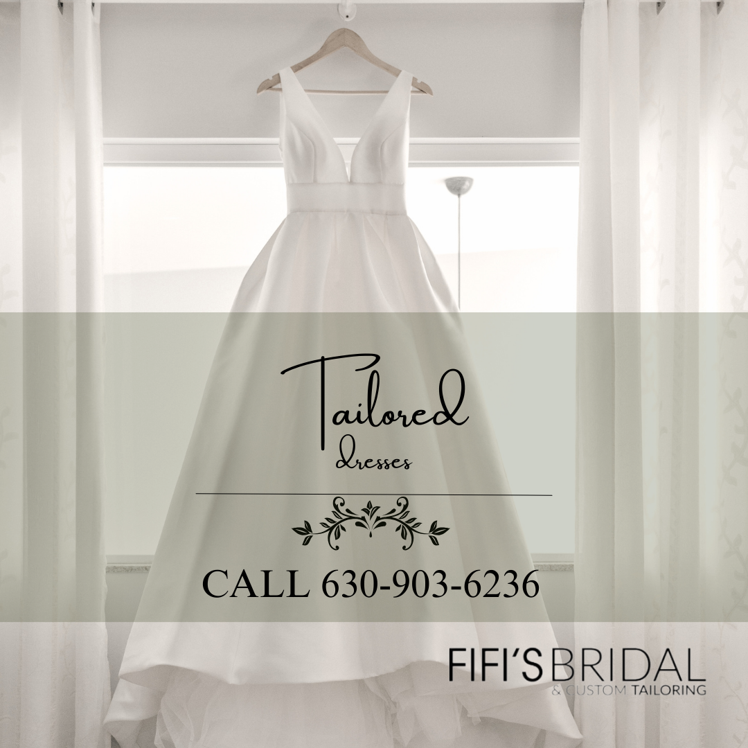 A tailored white dress is hanging on a hanger in front of a window.  Fifi's Tailoring in Elmhurst, IL