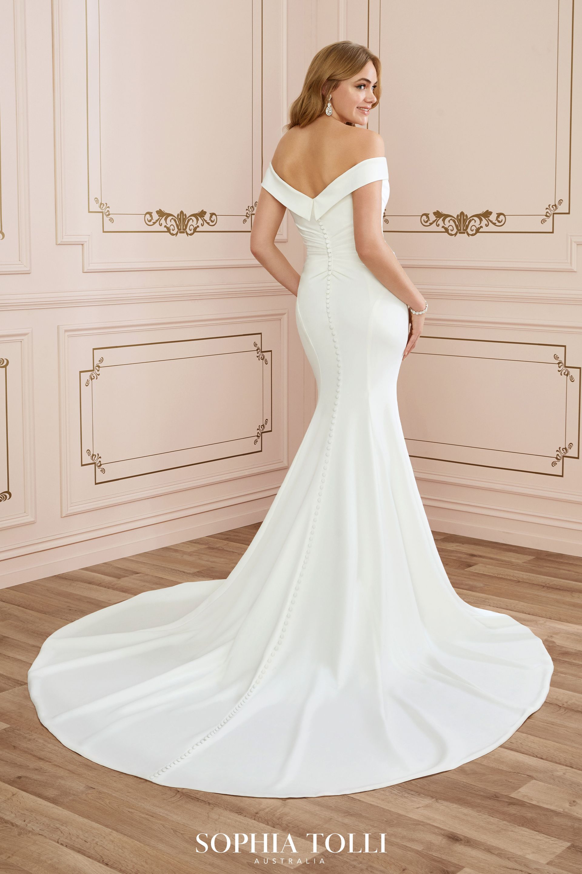 A woman is wearing a white off the shoulder wedding dress.