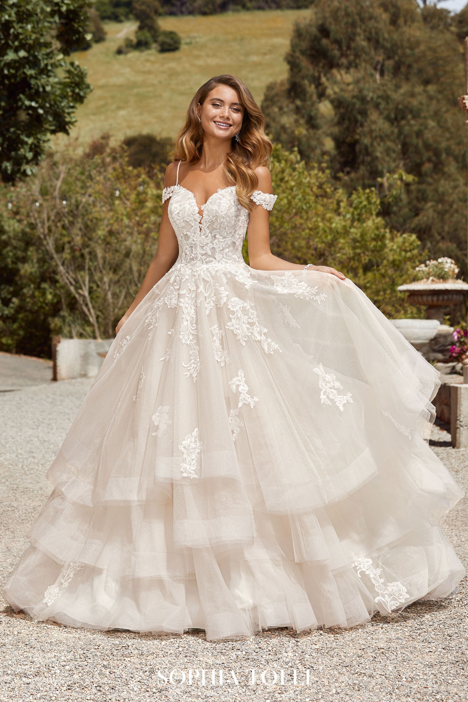 A woman in a wedding dress is standing on a gravel road.