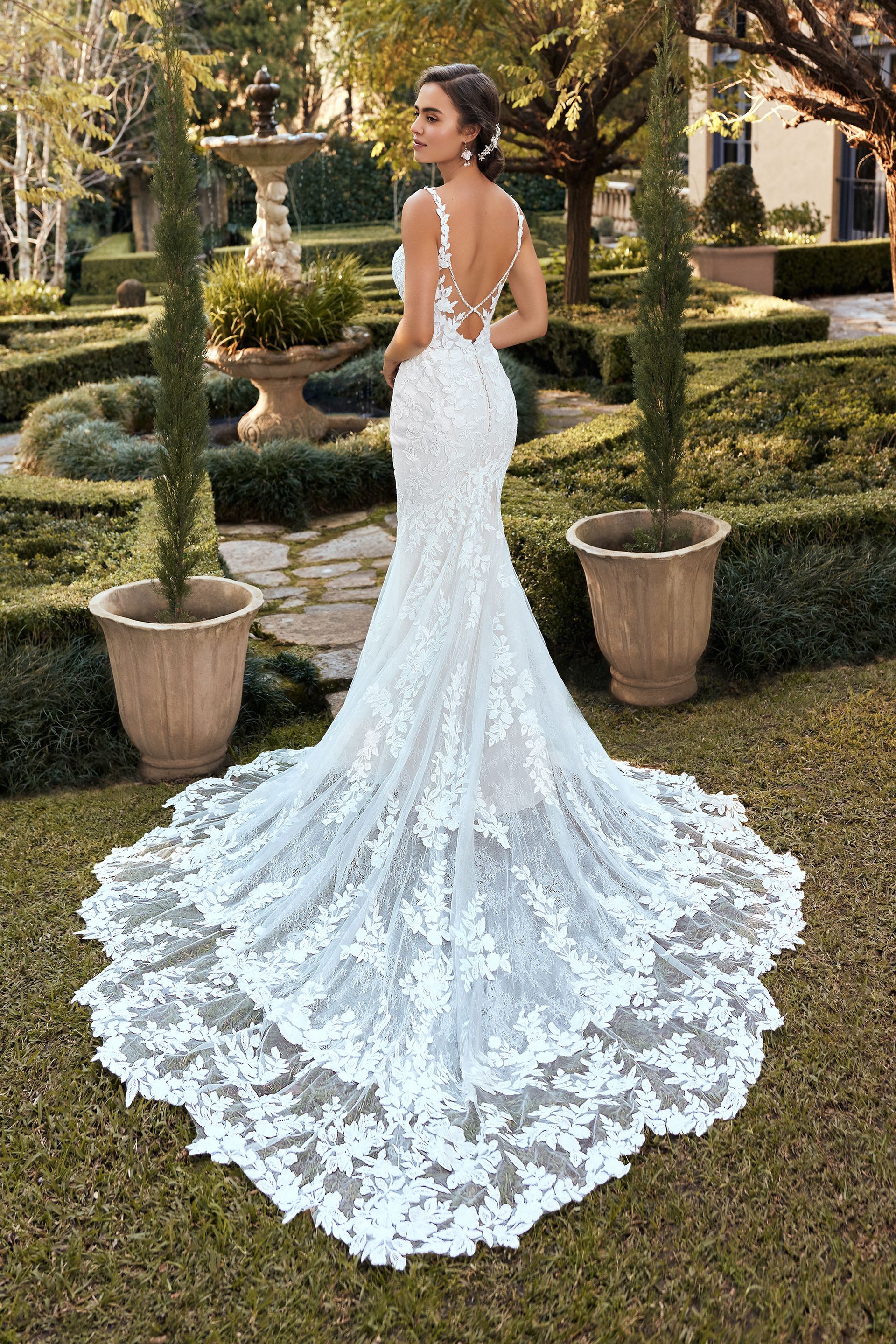 A woman in a white wedding dress is standing in a garden.