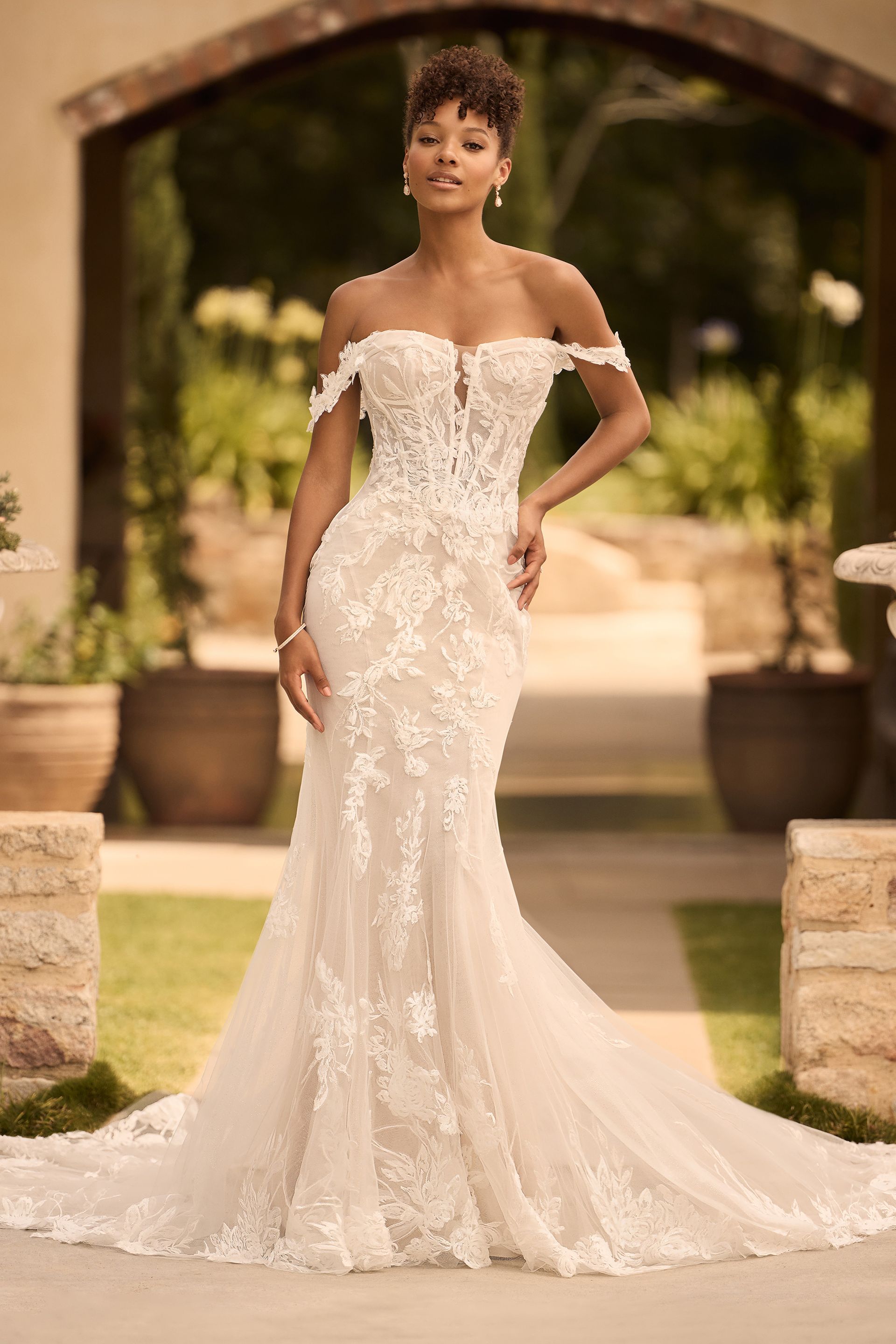 A woman in a white wedding dress is standing in front of a building.