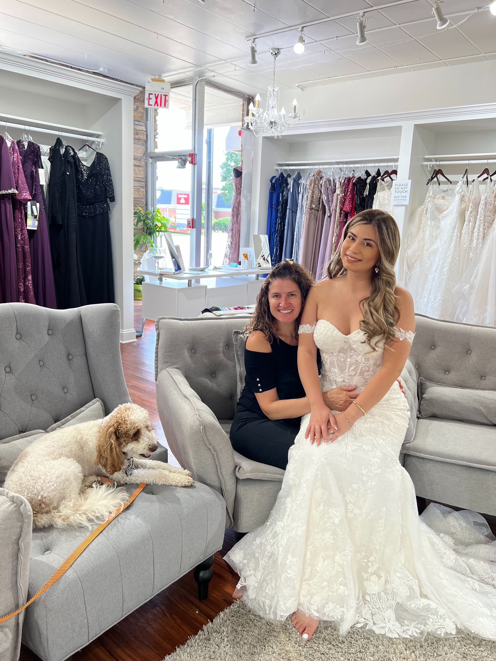Woman in wedding dress with another woman and dog in a bridal shop.