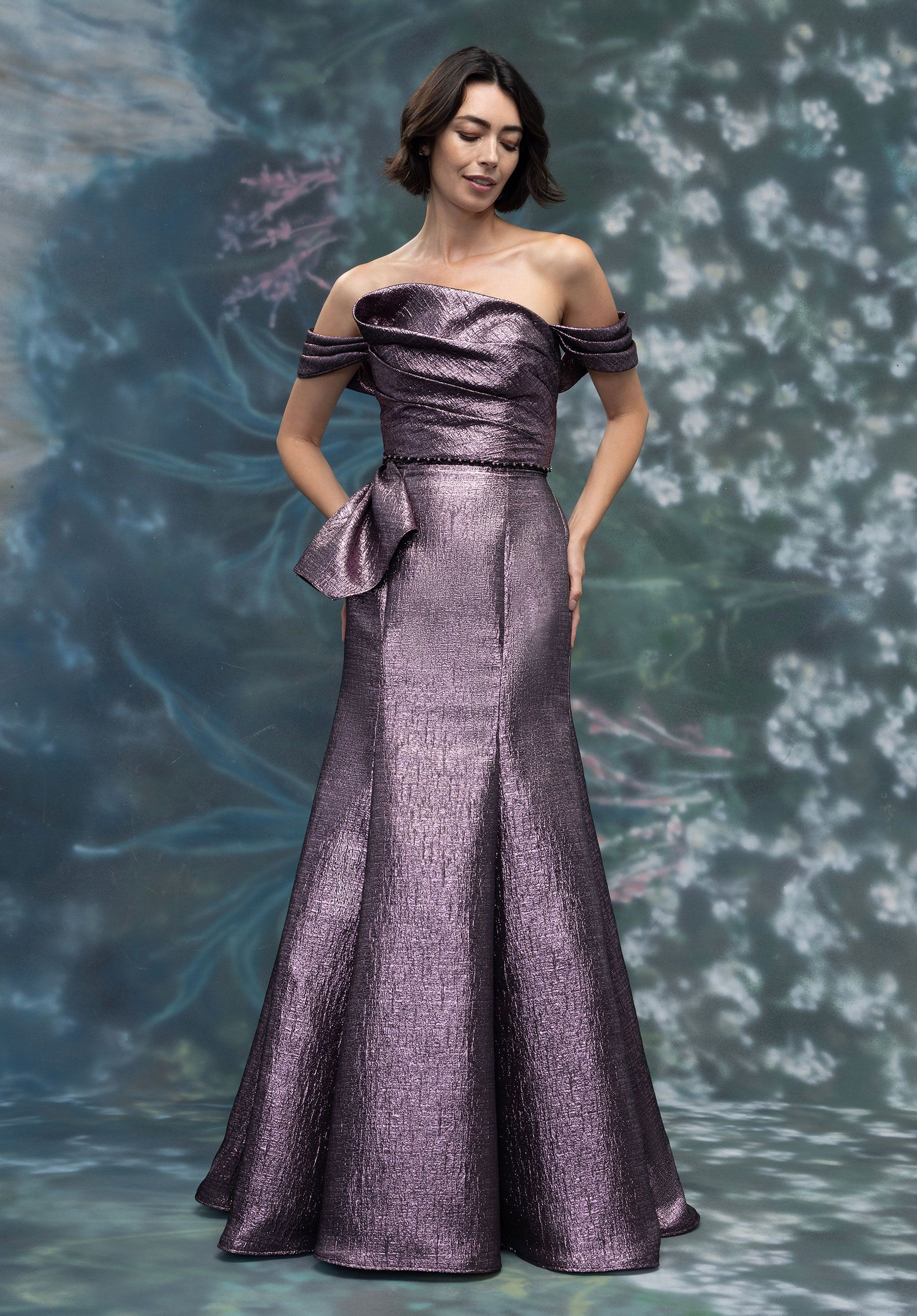 A woman in a long blue dress is standing in a living room.