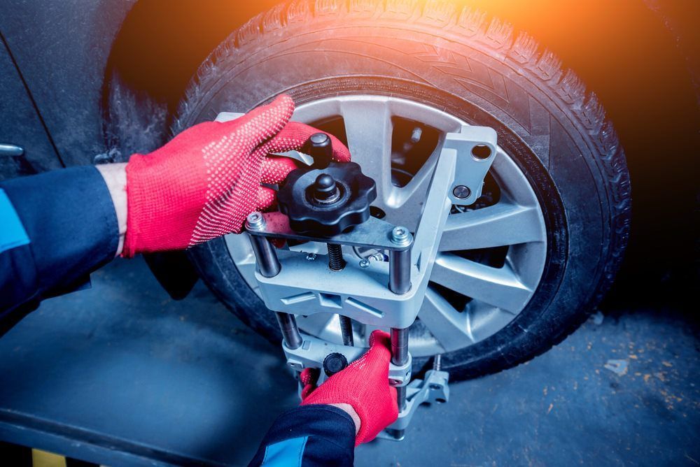 A Mechanic Adjusting Car Wheel Alignment Tool on A Car Tire — Dunn's Auto Repair in Bundaberg East, QLD