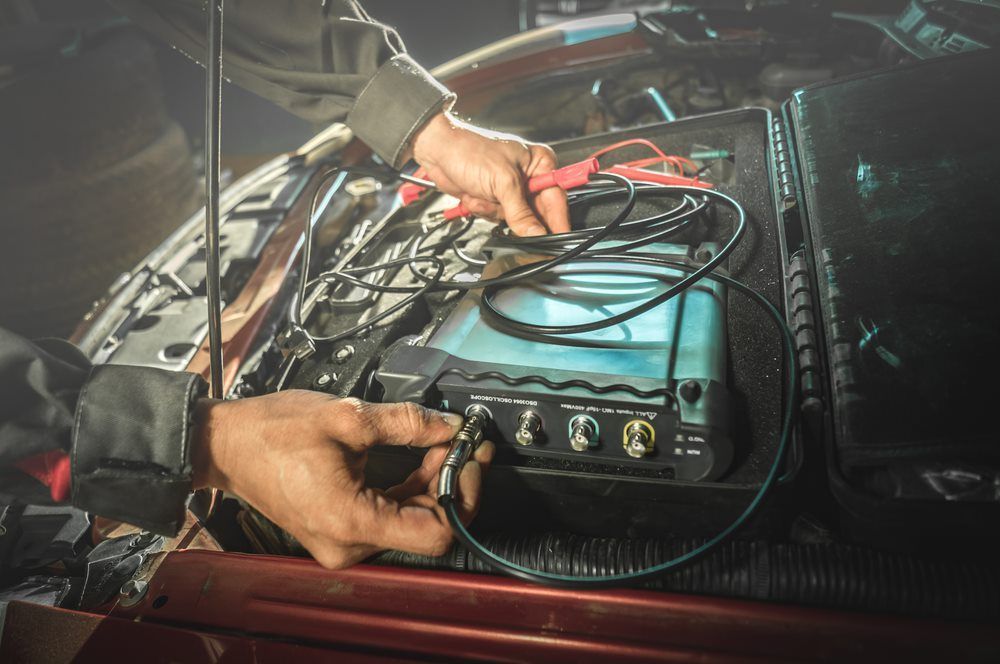 A Mechanic Connecting a Wire to A Diagnostic Machine — Dunn's Auto Repair in Bundaberg East, QLD
