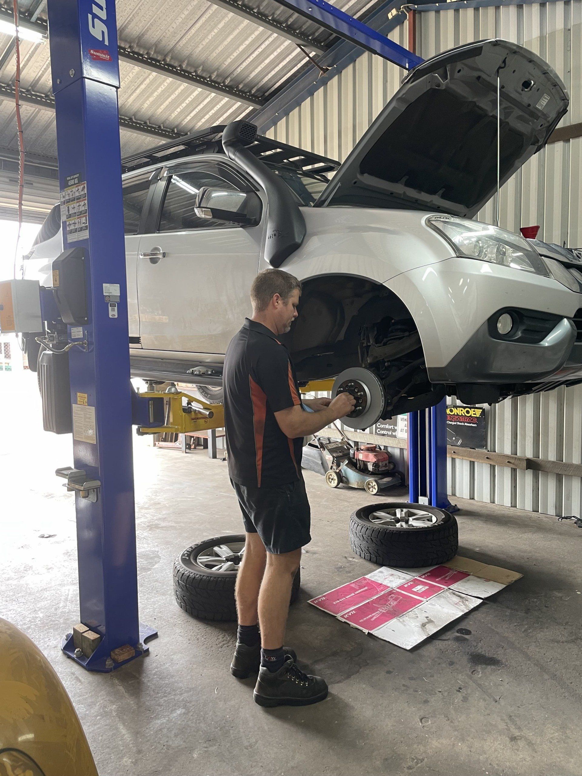 A Mechanic Working on A Car Raised on A Lift in A Garage — Dunn's Auto Repair in Bundaberg East, QLD