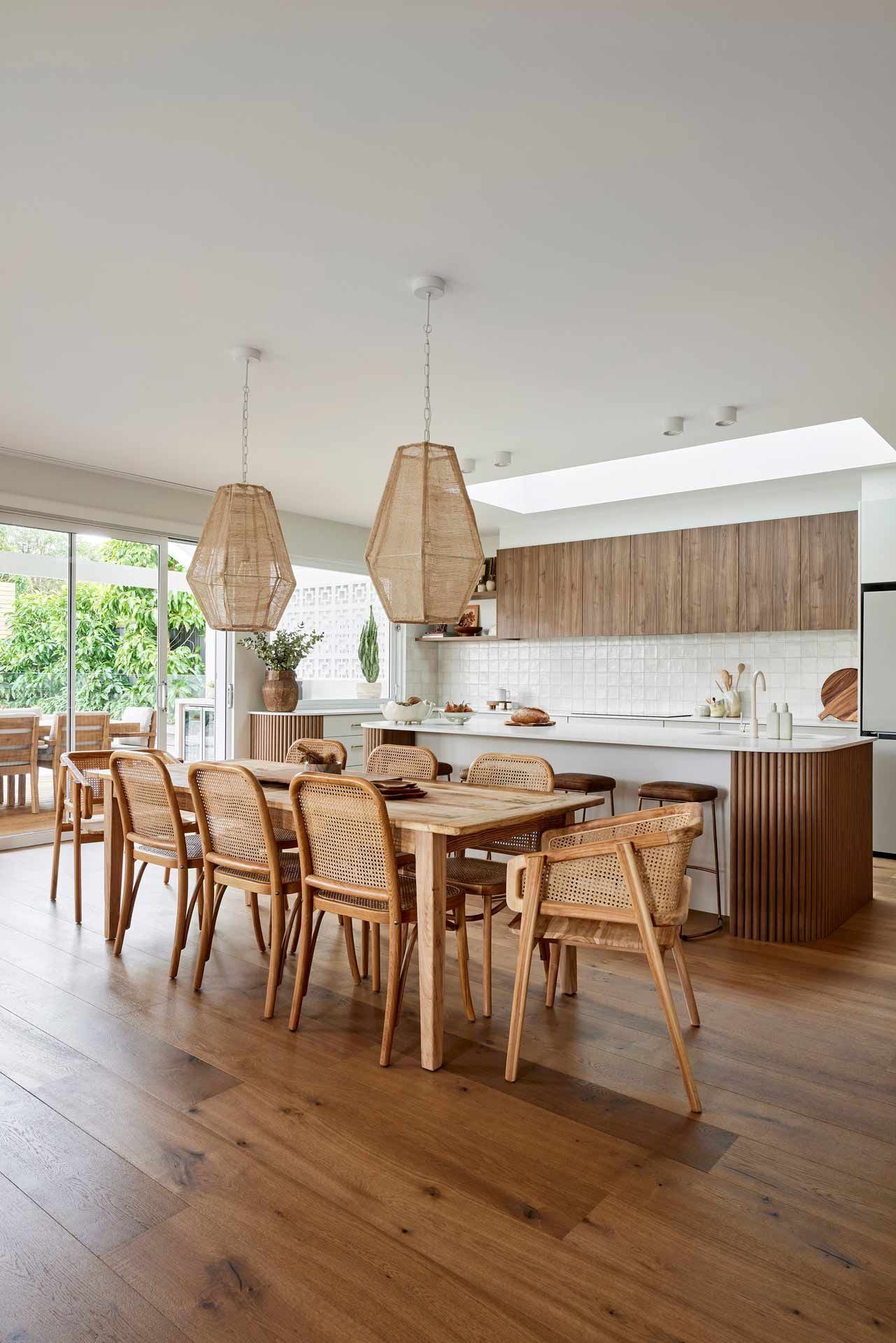 Dining room with wooden table, chairs, and pendant lights.