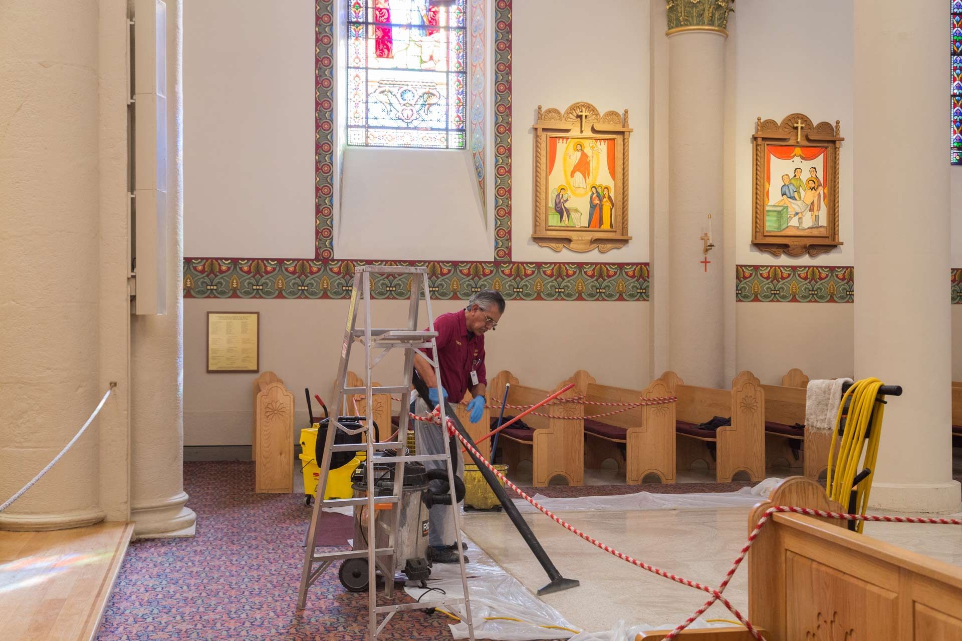A person vacuums inside a church.