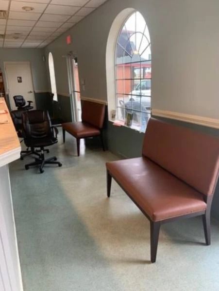 A waiting room with brown benches, a large arched window, and gray walls.