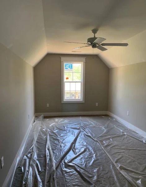 Bedroom interior with light tan walls, a white-framed window, and a ceiling fan.