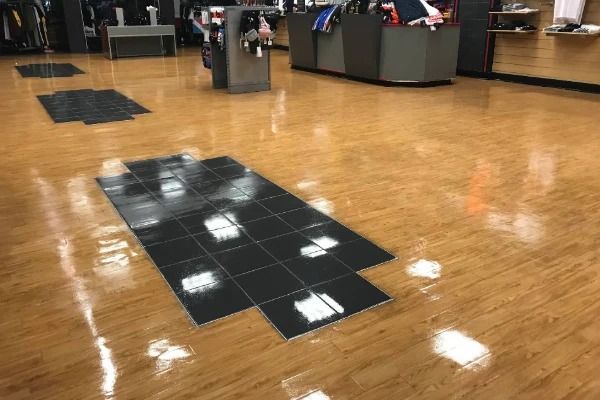Wooden store floor with black tiled mats.