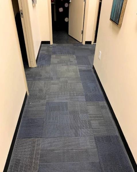 Narrow hallway with blue patterned carpet and off-white walls. Two doors are visible.